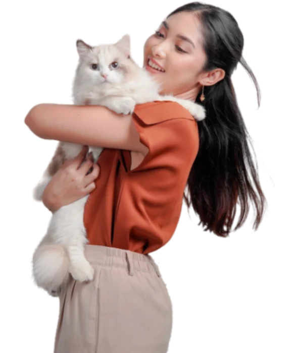 Femme souriante tenant un chat Ragdoll blanc et beige dans ses bras.